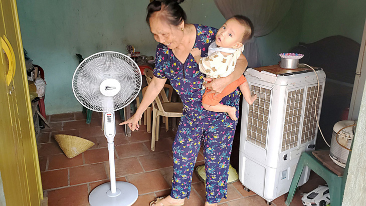Bà Nguyễn Thị Quý vui vẻ nhờ gió quạt sử dụng nguồn điện năng lượng mặt trời - Ảnh: TÂM LÊ