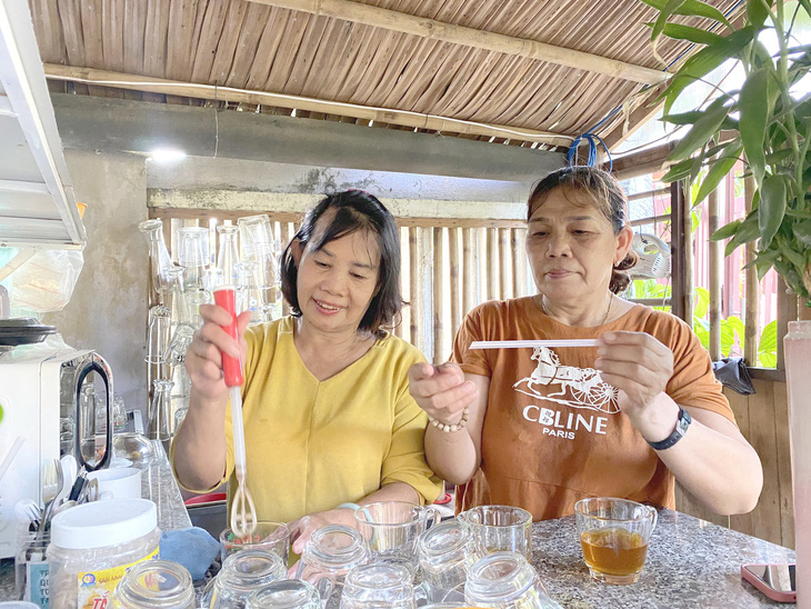 Bà Hoa (bên trái) bán nước trong cửa tiệm 0 đồng của gia đình bà dựng lên giúp gia đình bà Sang - Ảnh: B.D.