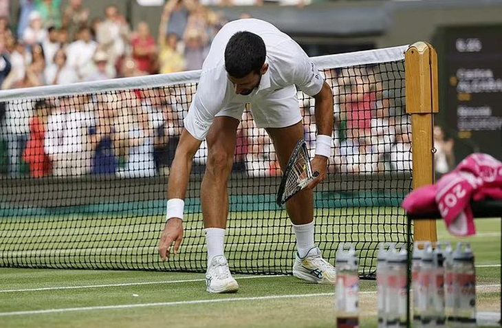 Novak Djokovic đập vợt vào cạnh lưới khi để mất break vào tay Alcaraz ở ván 5 - Ảnh: EPA