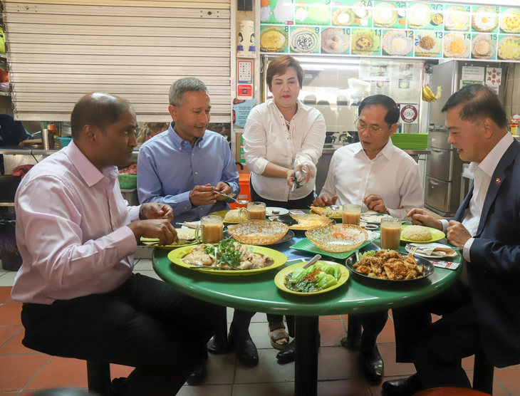 Bộ trưởng Bùi Thanh Sơn (áo trắng) và Ngoại trưởng Singapore Balakrishnan (áo xanh) cùng đại sứ hai nước thưởng thức bữa trưa bình dân ở khu ẩm thực Maxwell - Ảnh: P.H
