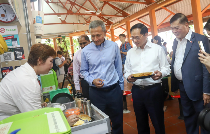 Bộ trưởng Bùi Thanh Sơn (áo trắng) và Ngoại trưởng Singapore Balakrishnan (áo xanh) thăm hàng ăn của chị Hạnh - Ảnh: P.H