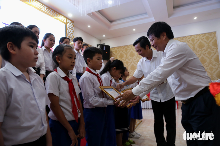 Ông Trần Trọng Dũng, phó chủ tịch Hội Nhà báo Việt Nam, tặng học bổng cho học sinh nghèo vượt khó trong chương trình Thắp sáng ngọn lửa tri ân - Ảnh: QUỐC NAM
