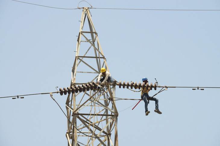 Hai thợ điện Ấn Độ bảo trì đường điện tại thành phố Ahmedabad hồi tháng 3-2018 - Ảnh: AFP