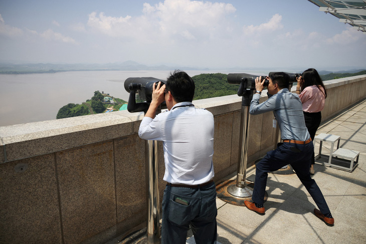 Du khách quan sát lãnh thổ Triều Tiên qua một cặp ống nhòm tại một đài quan sát gần khu phi quân sự ở thành phố Paju, Hàn Quốc, ngày 19-7 - Ảnh: REUTERS