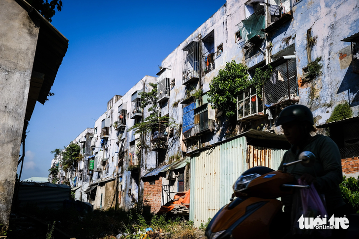 Người dân chạy xe qua phía sau hai khối nhà chung cư Hòa Minh - Ảnh: TẤN LỰC