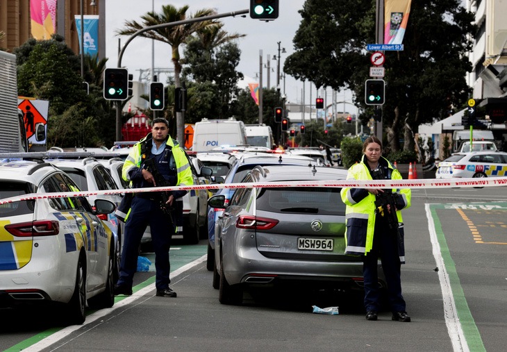 Cảnh sát có vũ trang đứng gác bên ngoài một công trường xây dựng sau vụ xả súng tại khu thương mại trung tâm thành phố Auckland, New Zealand ngày 20-7 - Ảnh: REUTERS