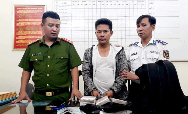 Vàng A Dông (giữa) cùng tang vật gồm 4 bánh heroin và một số vật chứng khác sau khi bị bắt quả tang giao dịch mua bán tại tỉnh Nam Định - Ảnh: Công an Nam Định
