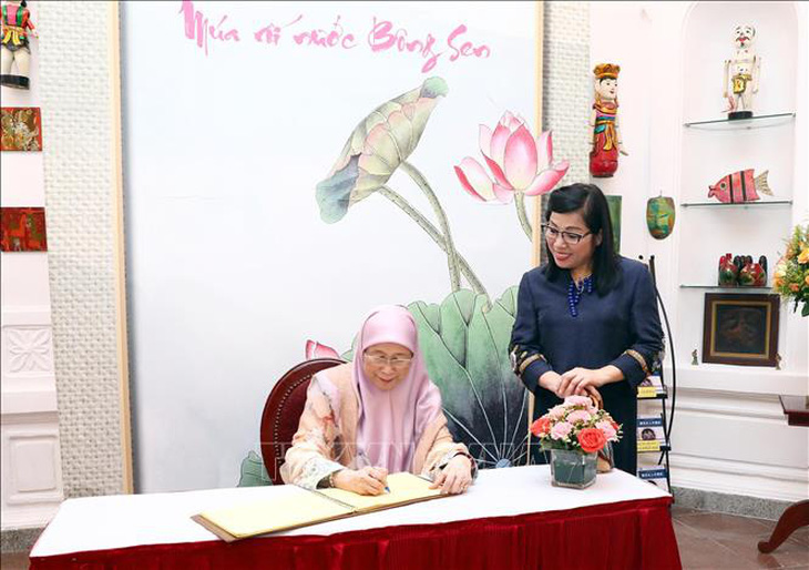 Phu nhân Wan Azizah Wan Ismail viết sổ lưu niệm tại nhà hát - Ảnh: TTXVN