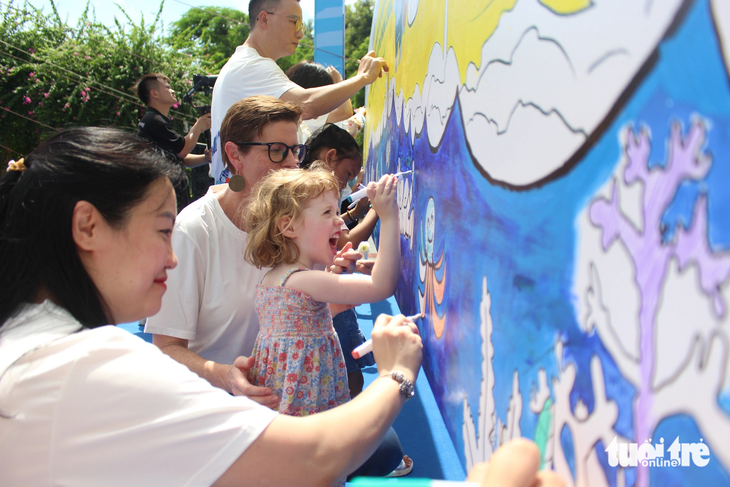 Đại diện WHO tại Việt Nam cùng con gái tô màu bức tranh tuyên truyền về phòng chống đuối nước tại sự kiện - Ảnh: DƯƠNG LIỄU