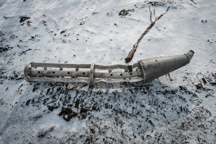 Vỏ bom chùm dạng tên lửa được cho là nằm trên mặt đất phủ đầy tuyết ở Zarichne, Ukraine ngày 6-2-2023 - Ảnh: AFP