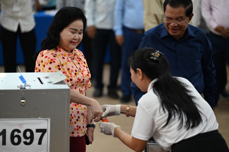 Bà Bun Rany (trái), phu nhân Thủ tướng Hun Sen, nhúng ngón tay vào lọ mực đánh dấu đã bỏ phiếu - Ảnh: AFP