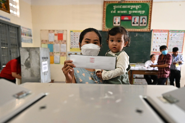 Nữ cử tri bế con đi bầu tại thủ đô Phnom Penh. Công tác bỏ phiếu sẽ kết thúc lúc 15h cùng ngày - Ảnh: AFP