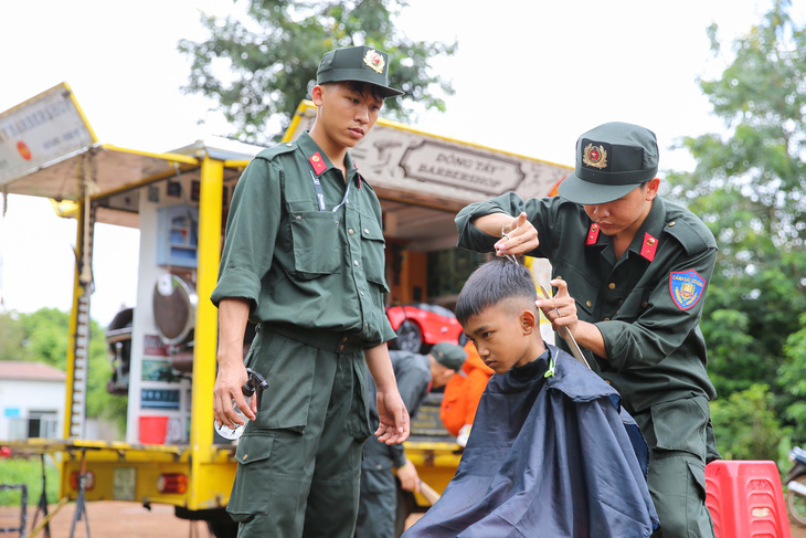 Các em nhỏ trên địa bàn Tây Nguyên được chiến sĩ cảnh sát cắt tóc miễn phí - Ảnh: NGUYỄN HẰNG