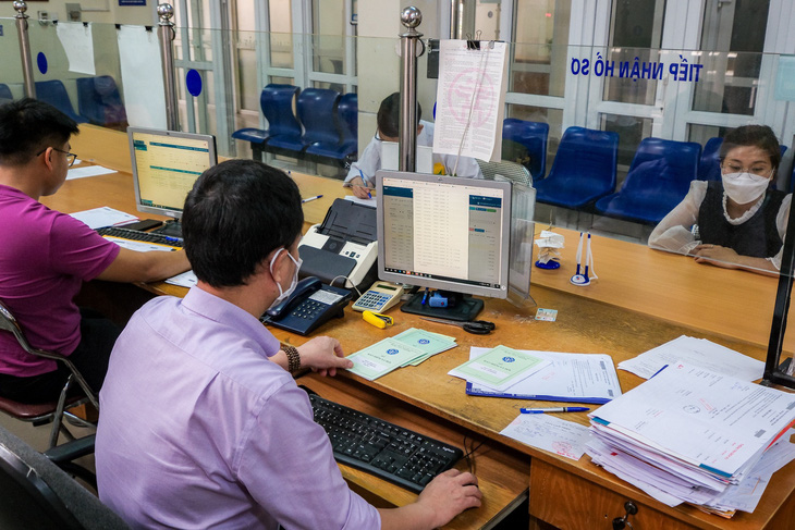 Cán bộ Bảo hiểm xã hội quận Hoàng Mai, Hà Nội xử lý hồ sơ của người dân đến làm thủ tục như lương hưu, trợ cấp, ứng dụng bảo hiểm số VssID - Ảnh: NAM TRẦN