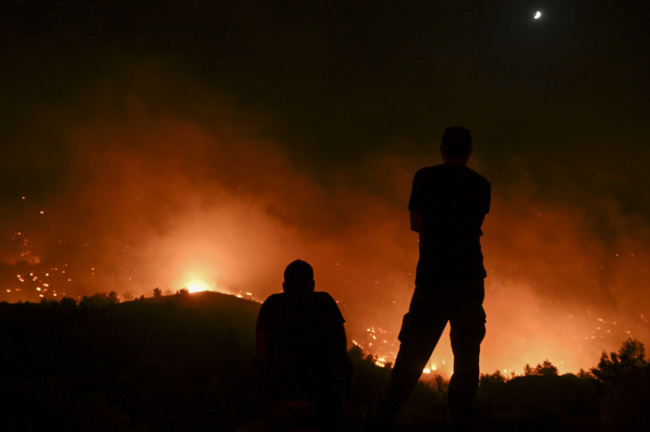 Mọi người quan sát các đám cháy rừng gần làng Malona trên đảo Rhodes của Hy Lạp vào ngày 23-7 - Ảnh: AFP