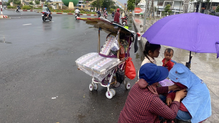 Chị Phạm Thúy Linh cùng bốn con nhỏ bày bán vé số dưới lòng đường Trần Hưng Đạo, phường 2, TP Sóc Trăng - Ảnh: K.TÂM