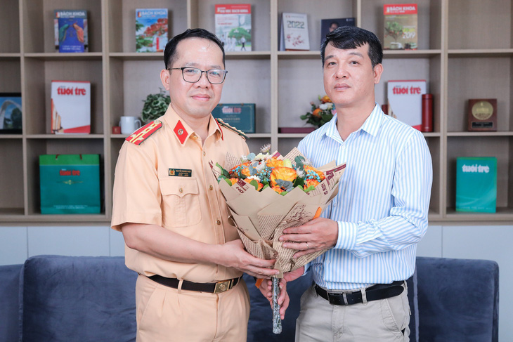 Đại diện báo Tuổi Trẻ tặng hoa cho Đại tá Nguyễn Quang Nhật (trái) - Ảnh: DANH KHANG