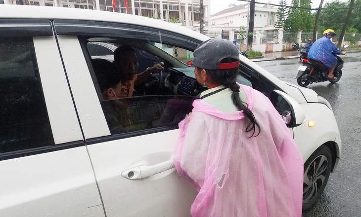 Bất chấp mưa gió, bé Mãi (12 tuổi) vẫn ào ra đường để mời chào khi xe đang dừng trụ đèn đỏ tại ngã tư đường Phan Ngọc Hiển - Trần Hưng Đạo (phường 5, TP Cà Mau, tỉnh Cà Mau) để bán vé số. Gia đình bé Mãi có năm người theo nghề bán vé số, mỗi ngày bình quân bán được hơn 500 tở.