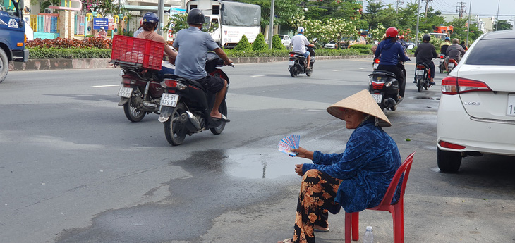 Chiều 25-7, một người phụ nữ lớn tuổi bắt ghế ngồi dưới lòng đường đường 3-2 (phường An Bình, quận Ninh Kiều, TP Cần Thơ) để bán vé số.