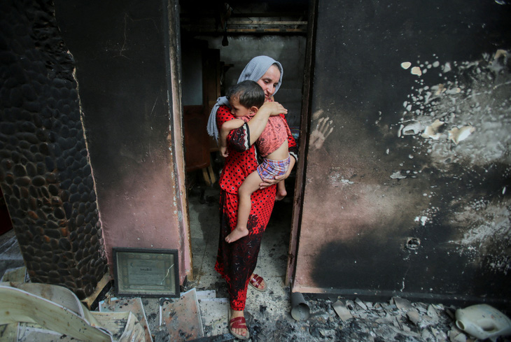 Chị Souhila Belkati ôm chặt con trong căn nhà bị cháy rụi, diễn ra sau vụ cháy rừng ở thành phố cảng Bejaia (Algeria) ngày 25-7 - Ảnh: REUTERS 