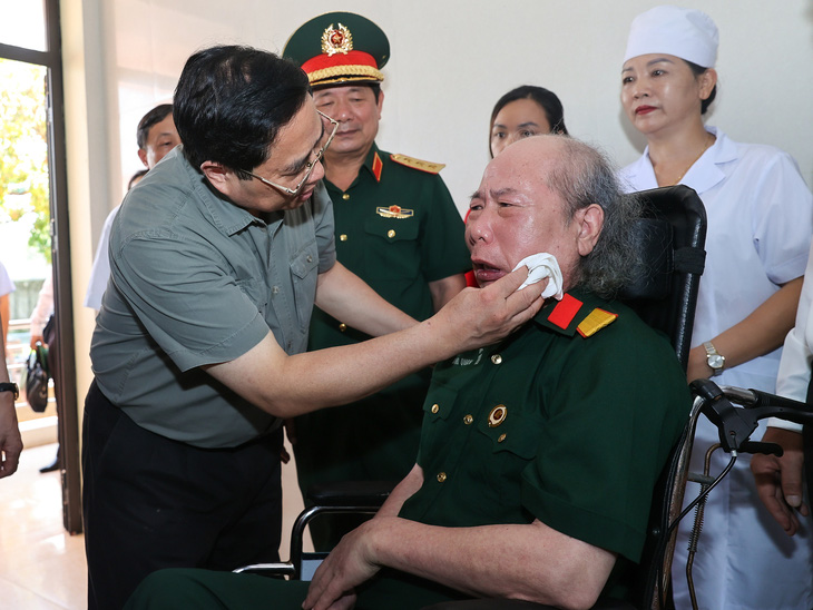 Thủ tướng Phạm Minh Chính chia sẻ với một thương binh tại Trung tâm Điều dưỡng thương binh Nho Quan, Ninh Bình - Ảnh: NHẬT BẮC