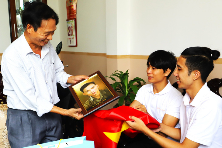 Nhóm Team Lee từ Hà Nội trao tận tay thân nhân các liệt sĩ những bức ảnh đã được phục dựng - Ảnh: THỤC NGHI