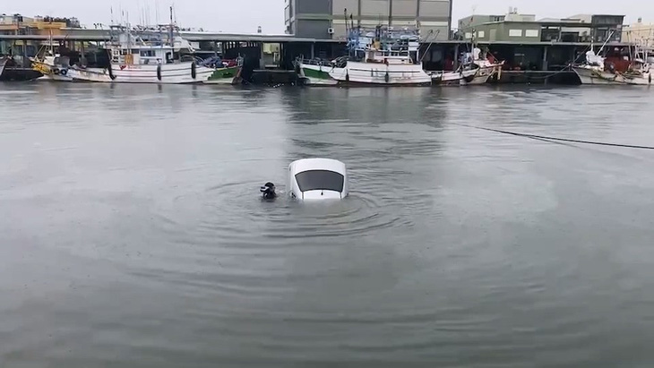 Cảnh giải cứu một người đàn ông khỏi ô tô sau khi vô tình lái xe xuống một bến thuyền ở Cao Hùng trong trận mưa lớn do bão Doksuri - Ảnh: TAIWAN NEWS