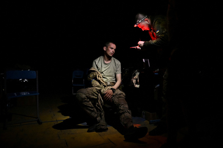 Nhân viên y tế nói chuyện với quân nhân Ukraine bị thương ở tuyến đầu tại Ukraine, ngày 27-7 - Ảnh: REUTERS