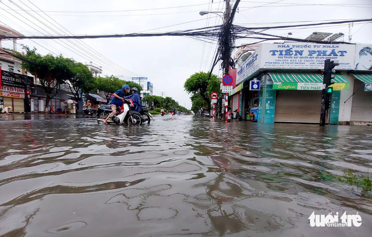 Ngã tư Đống Đa - Nguyễn Trung Trực (TP Rạch Giá) ngập sâu, xe chết máy nên người dân dẫn bộ - Ảnh: CHÍ CÔNG