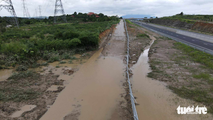 Nước ngập làm hư đường gom dân sinh cạnh tuyến cao tốc - Ảnh: ĐỨC TRONG