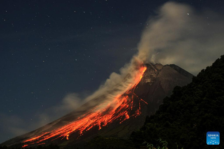 Ảnh chụp vào ngày 1-7-2023 cho thấy vật chất núi lửa phun ra từ núi Merapi khi nhìn từ làng Purwobinangun ở thành phố Yogyakarta, Indonesia - Ảnh: XINHUA