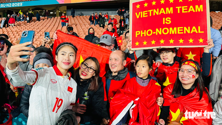 Thanh Nhã chụp ảnh với các CĐV Việt Nam bên cạnh biểu ngữ cổ động có món phở sau trận gặp Bồ Đào Nha - Ảnh: TR.N.