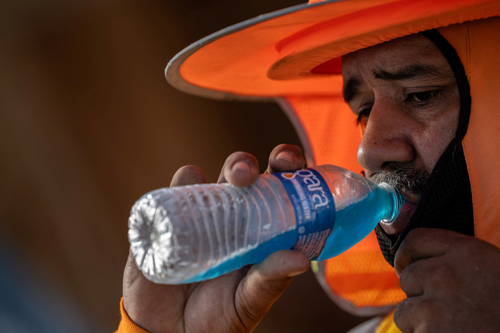 Một công nhân xây dựng tranh thủ uống nước lạnh giải nhiệt hôm 28-7. Sóng nhiệt khiến nhiệt độ tăng hơn 110 độ F (43 độ C) 27 ngày liên tiếp ở thành phố Scottsdale, bang Arizona (Mỹ) - Ảnh: REUTERS