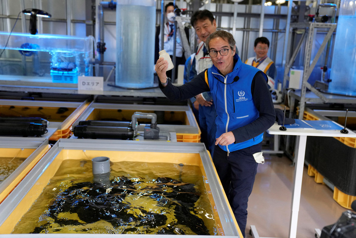 Ông Rafael Mariano Grossi, tổng giám đốc IAEA, cho cá ăn trong bể chứa đầy nước nhiễm xạ đã qua xử lý tại phòng thí nghiệm, khi ông đến thăm Nhà máy điện hạt nhân Fukushima ở Nhật Bản, ngày 5-7 - Ảnh: REUTERS