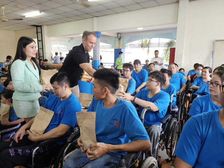Ông James trao trái cây cho những người khuyết tật ở Làng May Mắn - Ảnh: NGỌC ĐỨC