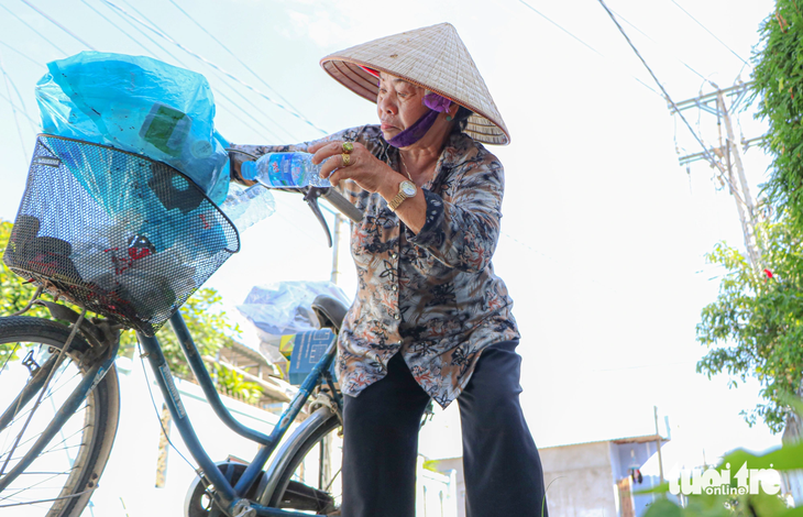 Bà Chích đạp xe đi các con đường trong thị trấn nhặt ve chai - Ảnh: DUY NGỌC