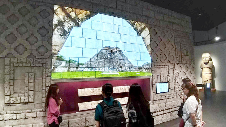 Khách tham quan bảo tàng đang nghe hướng dẫn viên giới thiệu về chữ viết Maya cổ đại - Ảnh: TÙNG NGỌC