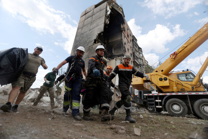 Nhân viên cứu hộ đưa một nạn nhân ra khỏi tòa nhà bị hư hại nặng nề ở Kryvyi Rig, Ukraine, ngày 31-7 - Ảnh: AFP