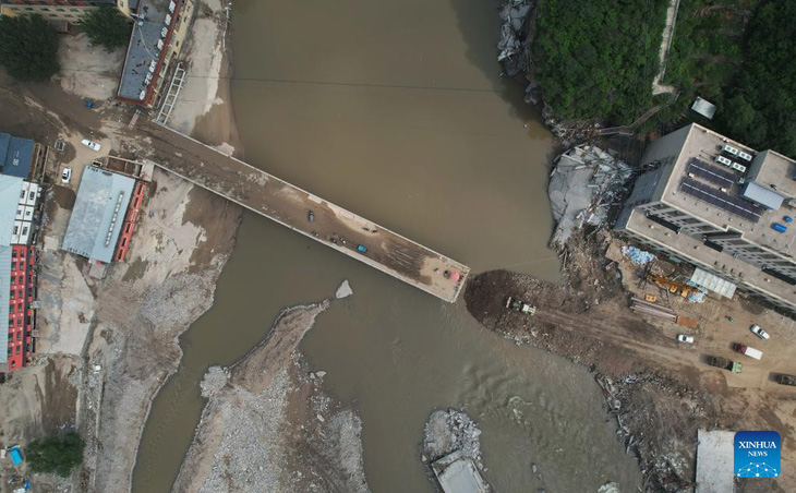 Lực lượng cứu hộ đang sửa lại một cây cầu dẫn vào làng Liujahe ở tỉnh Hà Bắc, Trung Quốc hôm 9-8 - Ảnh: TÂN HOA XÃ