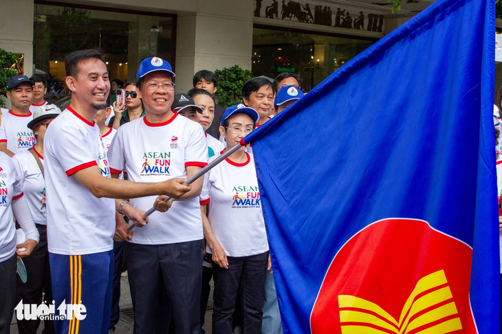Chủ tịch UBND TP.HCM Phan Văn Mãi (bên phải) và Tổng lãnh sự Indonesia tại TP.HCM Agustaviano Sofjan giương cờ ASEAN để khai mạc chương trình ASEAN Fun Walk sáng 12-8 - Ảnh: NGỌC ĐỨC