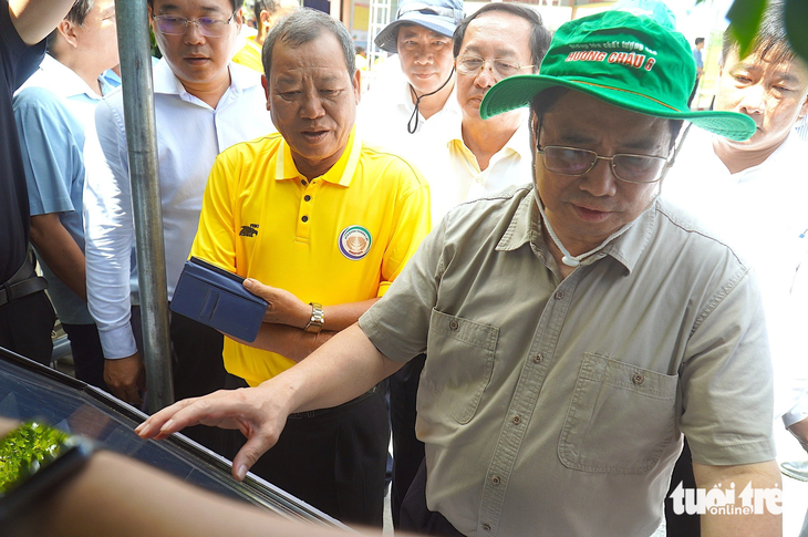 Thủ tướng Phạm Minh Chính xem máy cảm biến theo dõi các chỉ số trên cánh đồng - Ảnh: MẬU TRƯỜNG