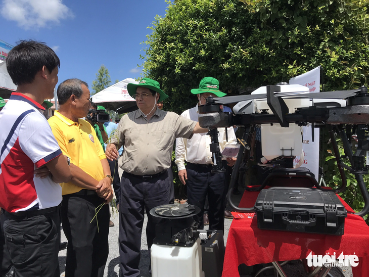 Thủ tướng Phạm Minh Chính nghe nông dân giới thiệu các máy cơ giới công nghệ cao - Ảnh: ĐẶNG TUYẾT