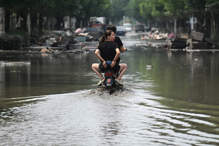 Người dân địa phương đi trên con phố ngập nước do mưa lớn ở thành phố Trách Châu, tỉnh Hà Bắc, miền Bắc Trung Quốc, ngày 9-8. Trung Quốc hứng chịu những trận mưa lớn kỷ lục trong những tuần gần đây, làm hư hại cơ sở hạ tầng và ngập lụt ở nhiều khu vực. Ít nhất 15 người đã chết và 22 người mất tích ở tỉnh Hà Bắc giáp thủ đô Bắc Kinh - Ảnh: AFP