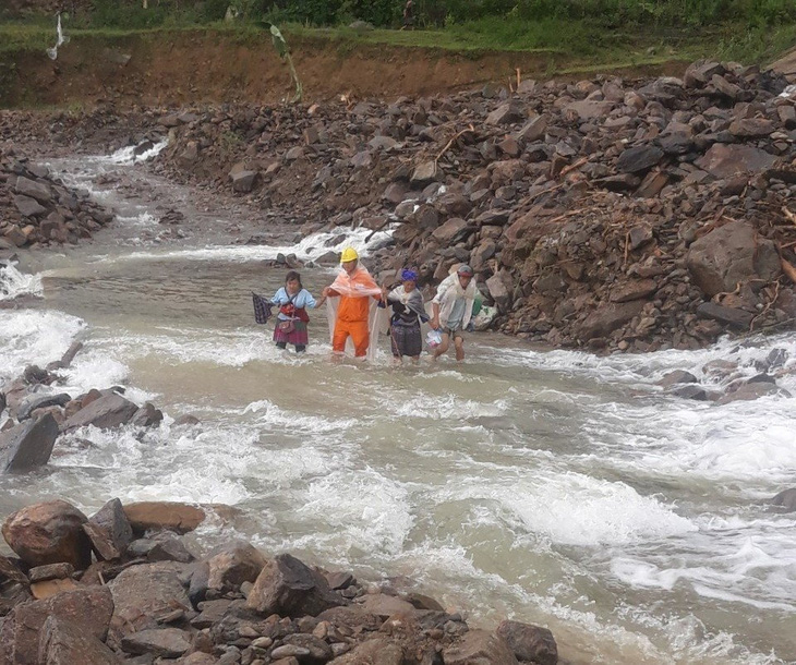 Công nhân Điện lực Than Uyên, PC Lai Châu giúp người dân qua suối