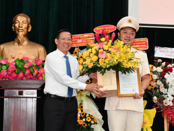 Chủ tịch UBND TP.HCM Phan Văn Mãi chúc mừng tân Phó giám đốc Công an TP.HCM Nguyễn Đình Dương - Ảnh: VIỆT DŨNG