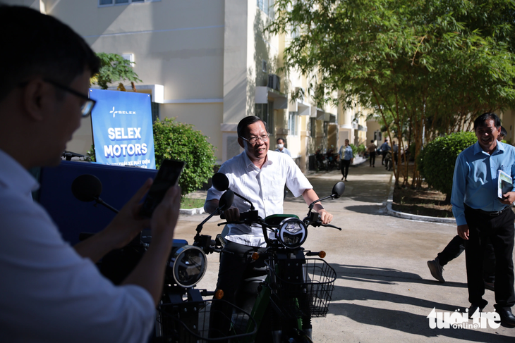 Chủ tịch Phan Văn Mãi đi thử xe máy điện được trưng bày bên ngoài hội thảo - Ảnh: TIẾN LONG