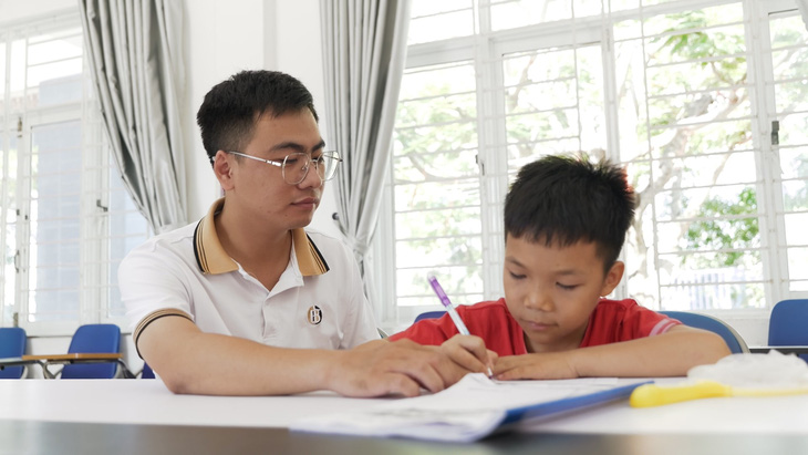 Nguyễn Quang Hiếu hướng dẫn các em nhỏ học tập tại Trung tâm Nuôi dạy trẻ mồ côi Hoa Mai - Ảnh: Đ.H.