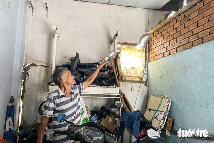 Ông Nguyễn Văn Quang (69 tuổi, ngụ tại số nhà 28 Phú Định) chỉ cho phóng viên thấy những vết nứt toác khắp căn nhà. Ông Quang đã dùng xi măng để trám tạm nhưng vẫn không ăn thua - Ảnh: TIẾN QUỐC