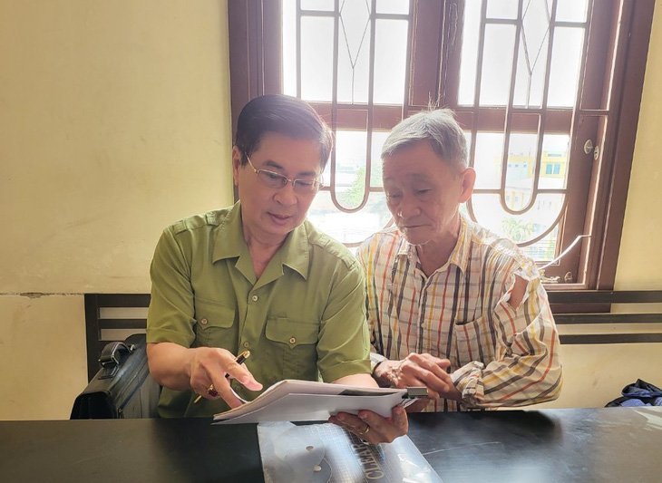 Ông Trịnh Dân Cường (phải) cùng người đại diện nghiên cứu hồ sơ vụ kiện đòi bồi thường oan sai - Ảnh: Đ.T.