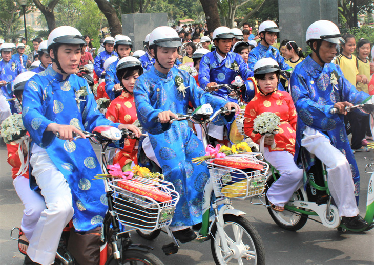Các cô dâu, chú rể diễu hành bằng xe đạp điện qua một số tuyến đường trung tâm TP.HCM trước khi đến nơi tổ chức lễ cưới tập thể - Ảnh: Q.LINH